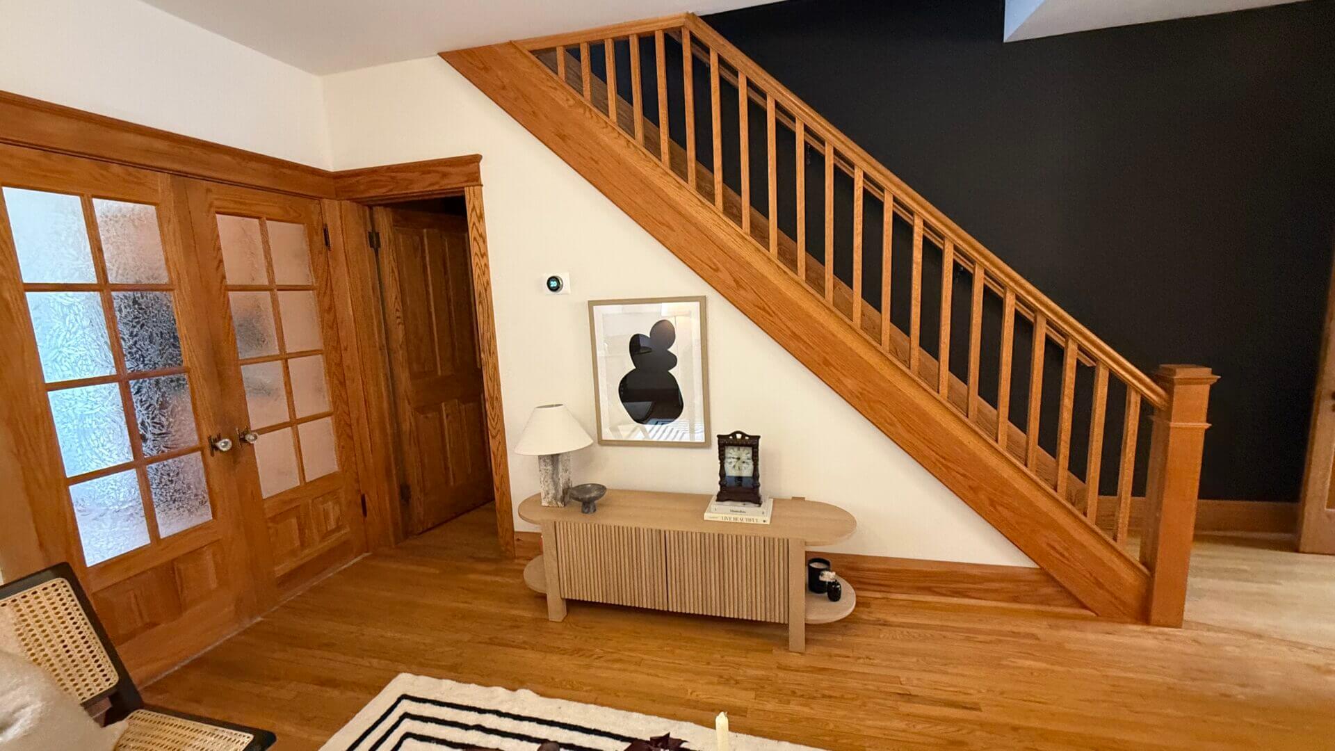 Modern hallway with wooden staircase and decor.