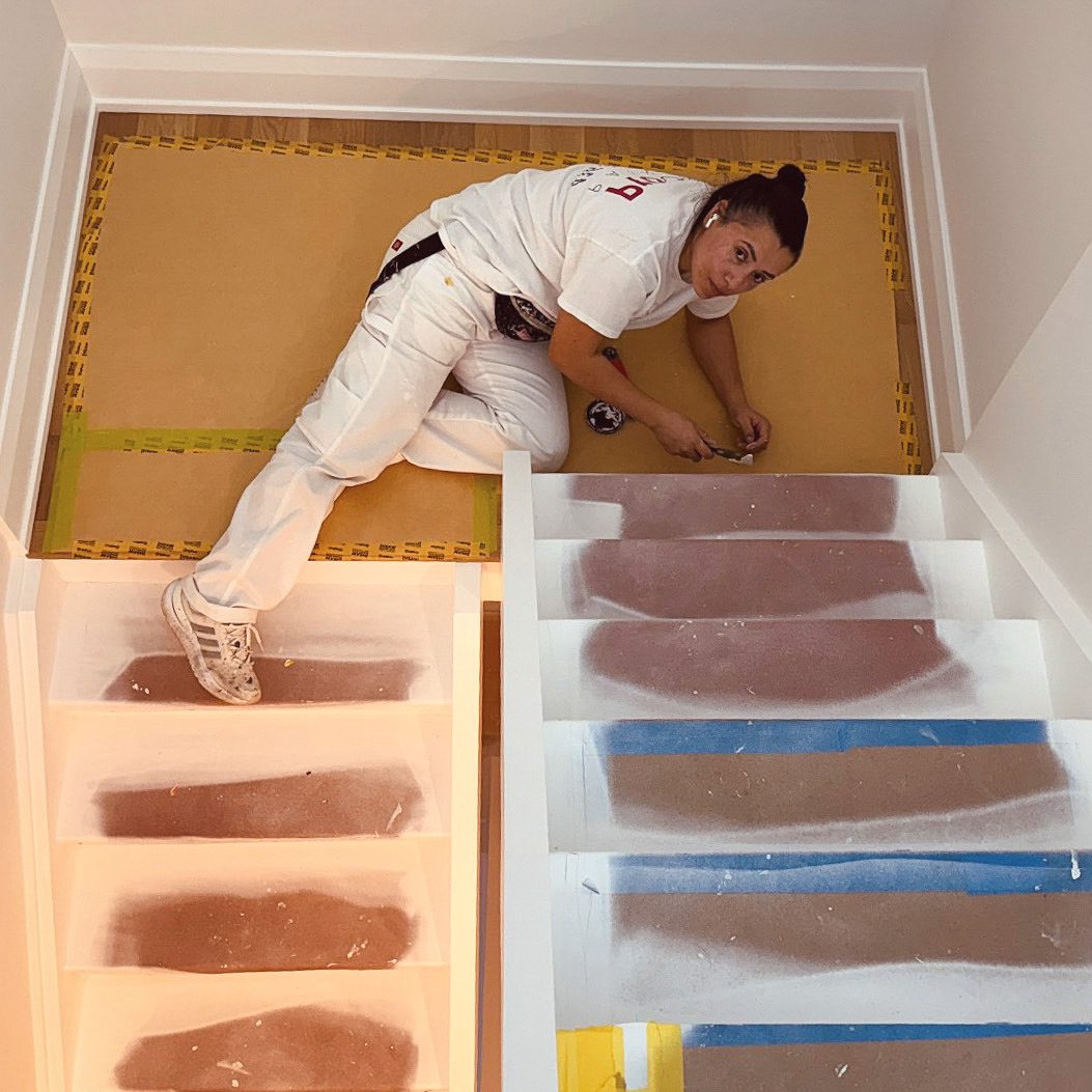 A person testing paint colors on a wall in a small room.