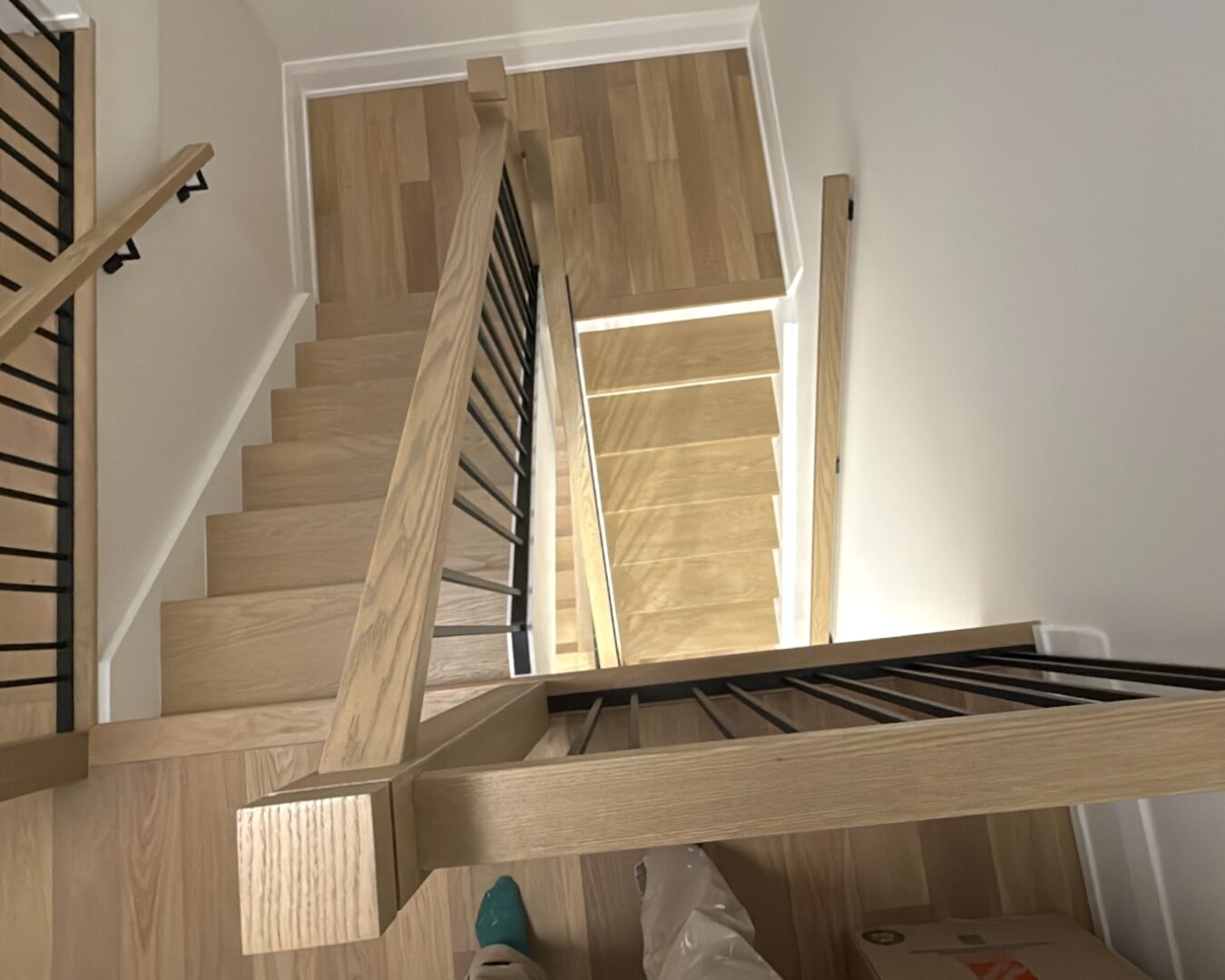 Top-down view of a wooden staircase with metal railings in a modern home.