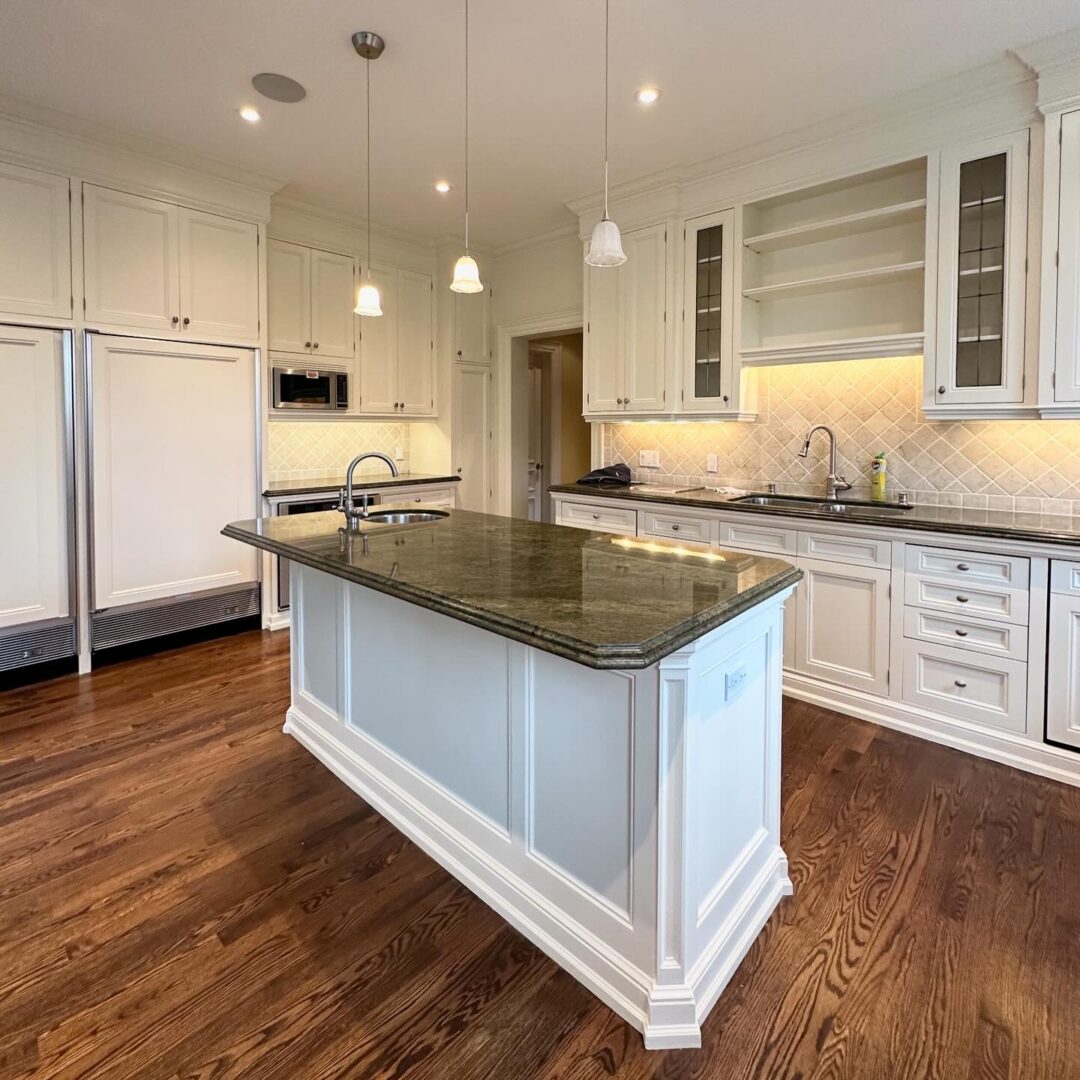 Modern kitchen with white cabinetry and granite island.