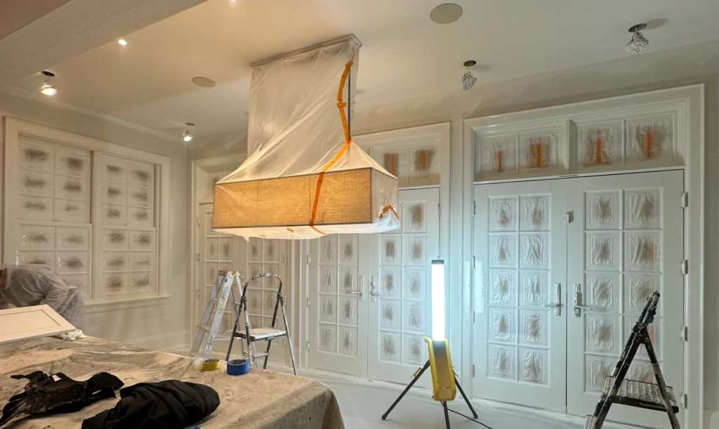 A suspended wooden light fixture hangs in a room under renovation.