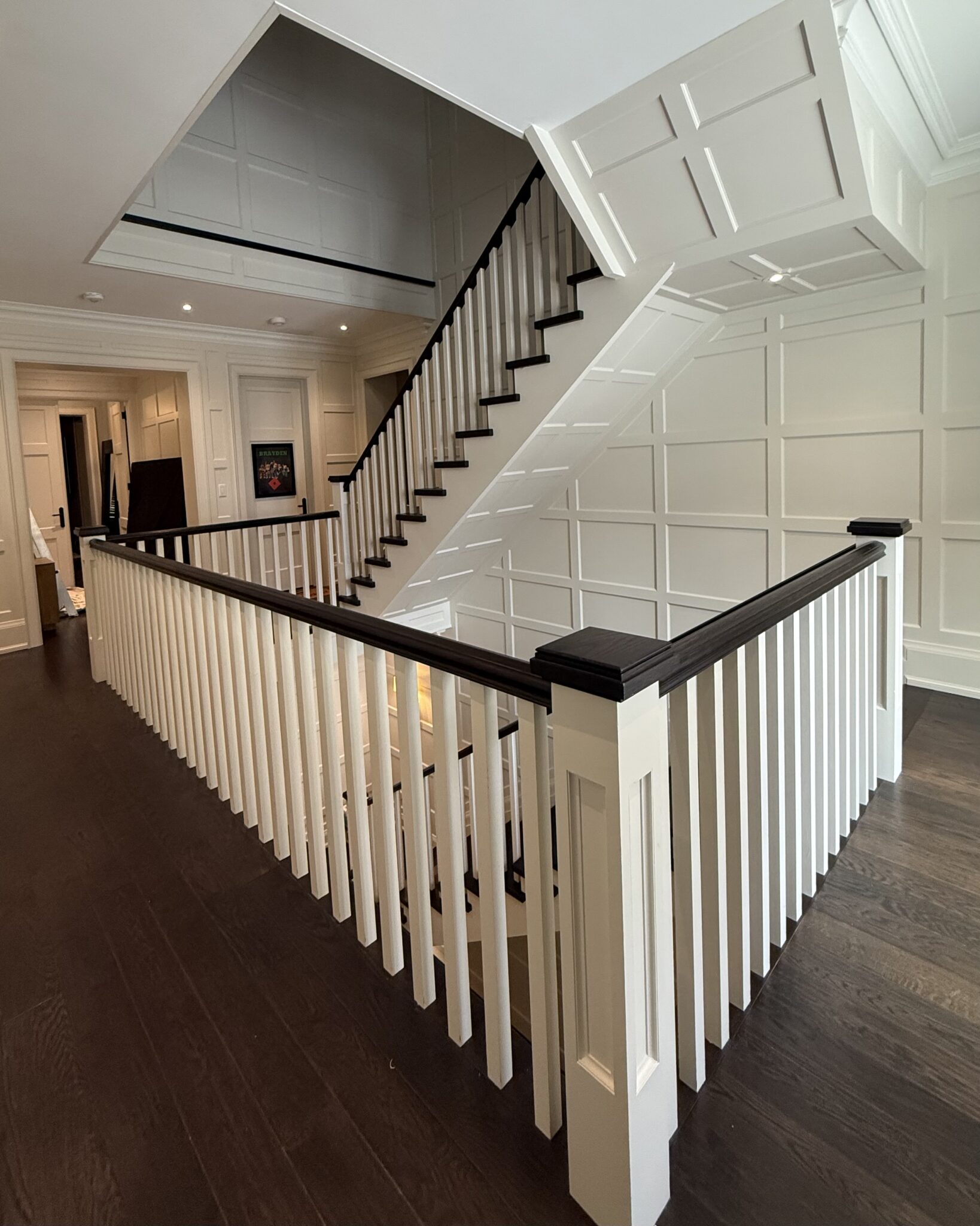 Modern staircase with white spindles and dark wood handrail.