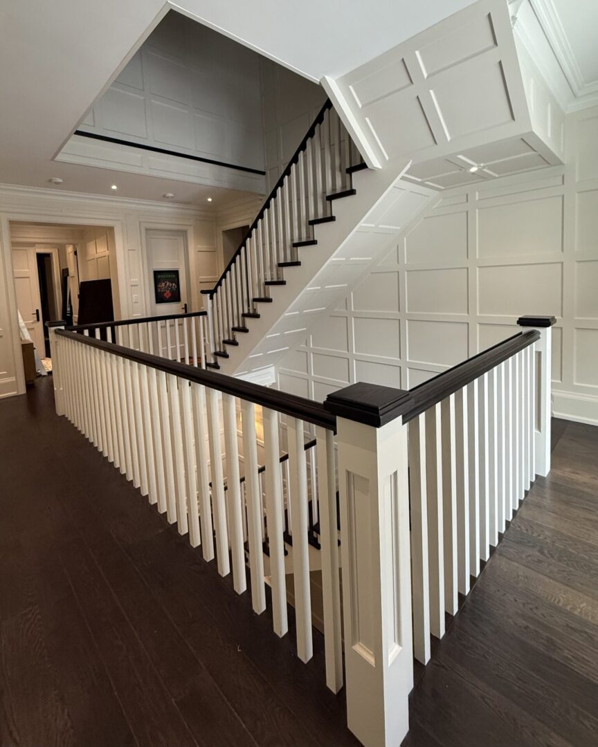 Modern staircase with white spindles and dark wood handrail.