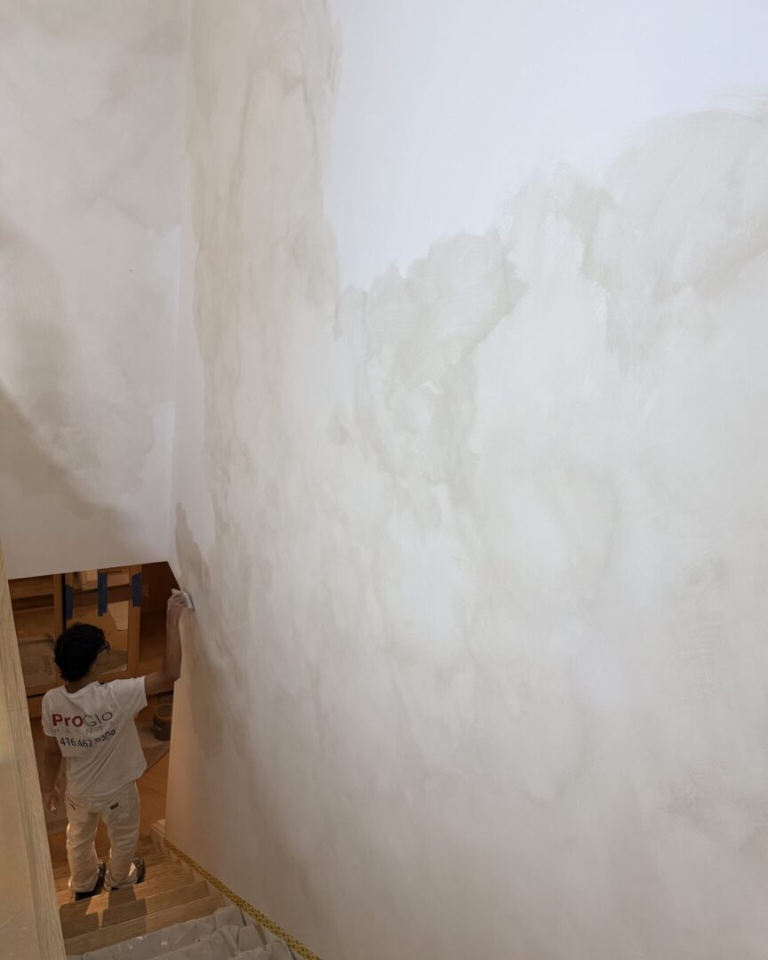 Person standing near a wall with a painting of a woman.