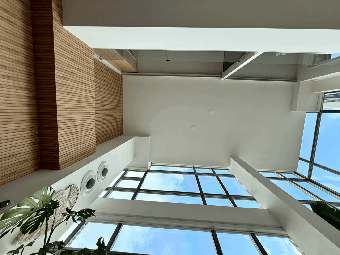 Looking up at a ceiling with windows and a wooden wall.