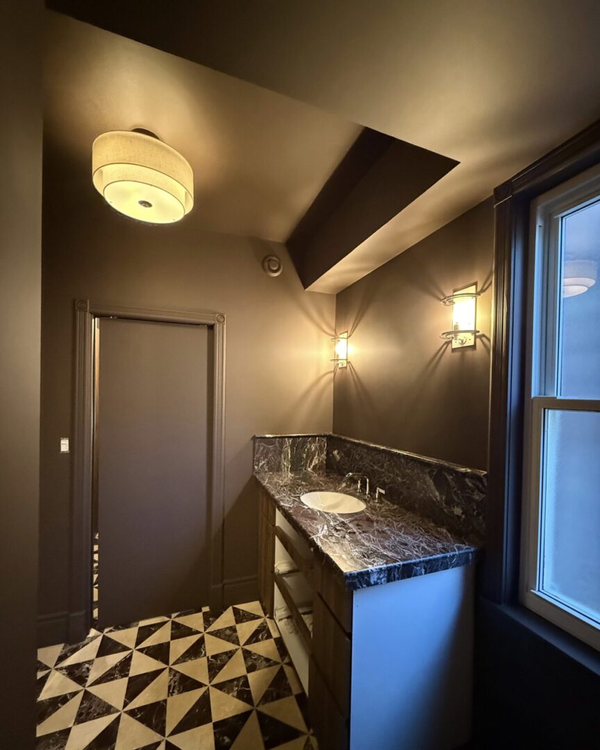 Modern bathroom with geometric floor tiles and marble countertop.