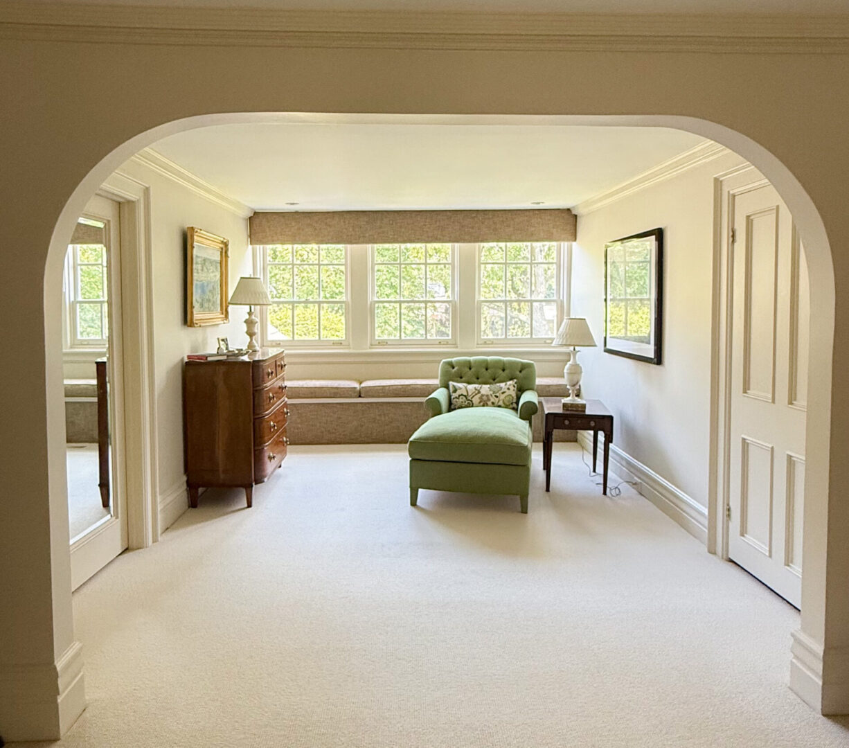 Bright living room with arched entry and large window seating.