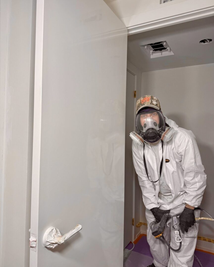 Person in protective gear painting a wall.
