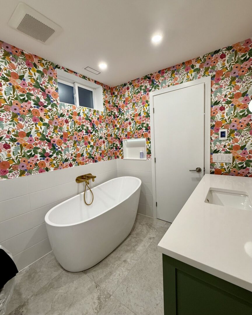 Modern bathroom with floral wallpaper and freestanding bathtub.