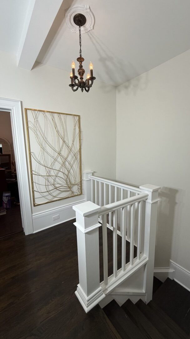 Elegant hallway with a white railing and framed abstract art.