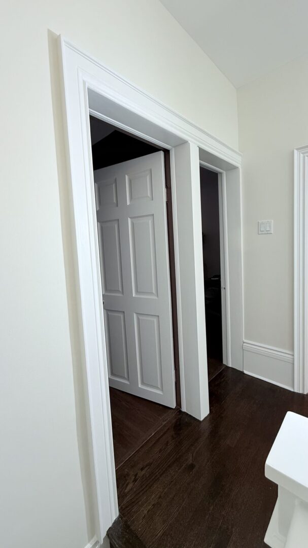 Partially open white interior door revealing a dark room.