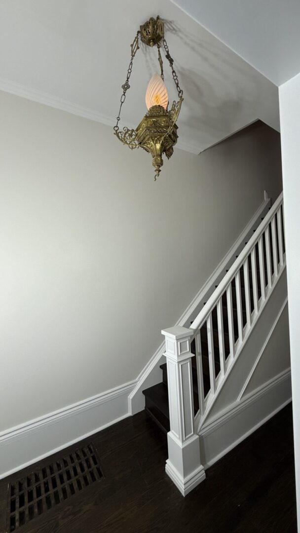 A white staircase with a decorative hanging light fixture.