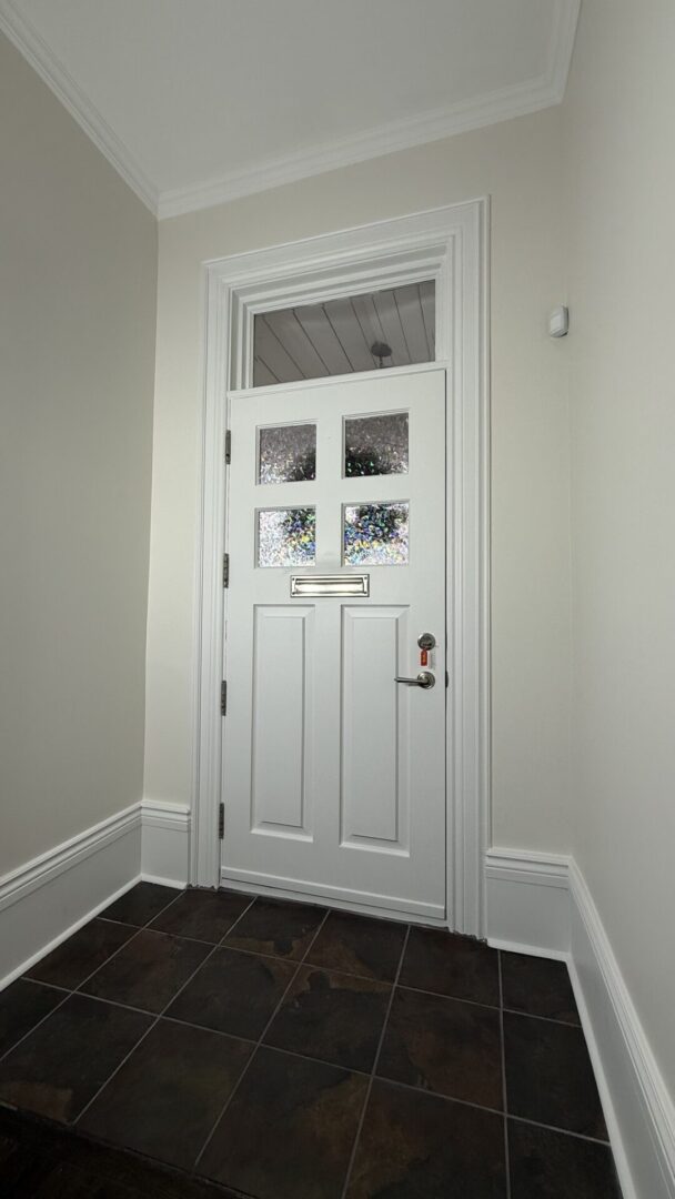 White wooden door with glass panels and a brass handle in a modern interior.