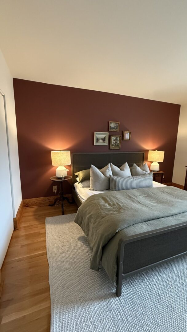 Cozy bedroom with a dark accent wall and warm lighting.