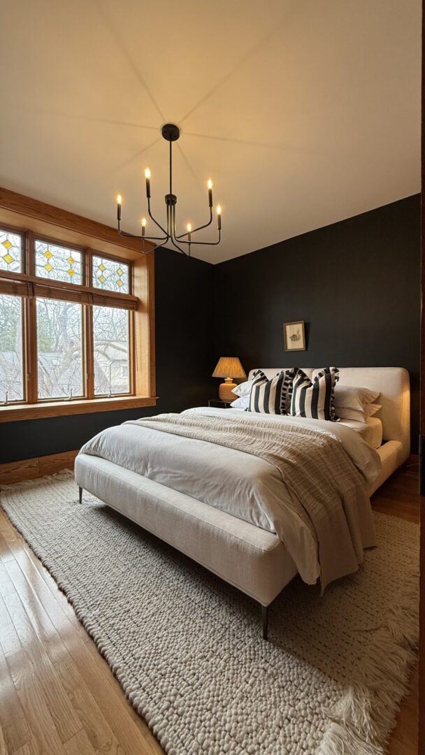 Cozy bedroom with a large window, dark accent wall, and modern bedding.