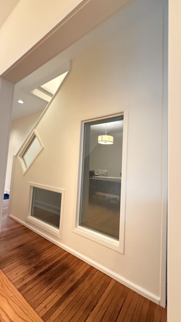 Interior wall with two unique geometric windows and a rectangular window.