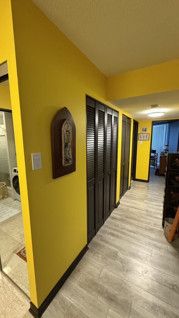 Bright yellow hallway with dark wooden closet doors and light flooring.