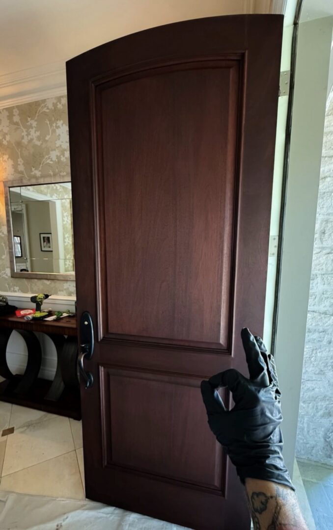 Dark wooden door with a brass doorknob and a black umbrella hanging on the handle.