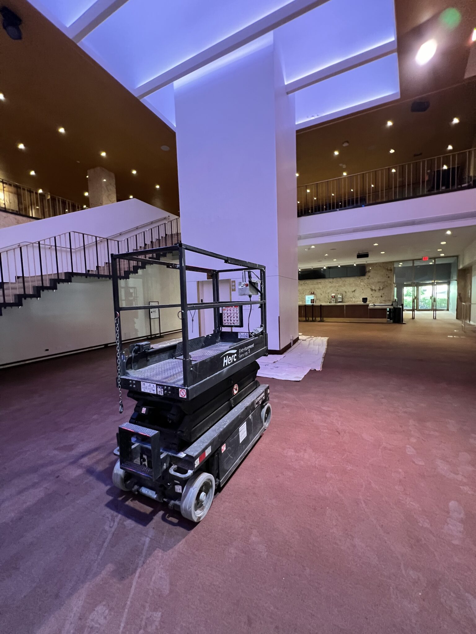 A robot with a camera rig in a spacious lobby area.