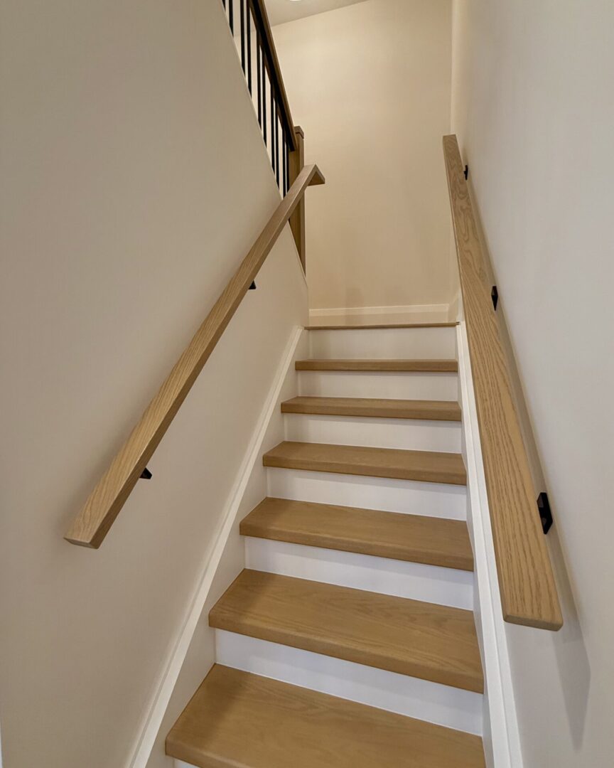 Simple wooden staircase with handrails on both sides.