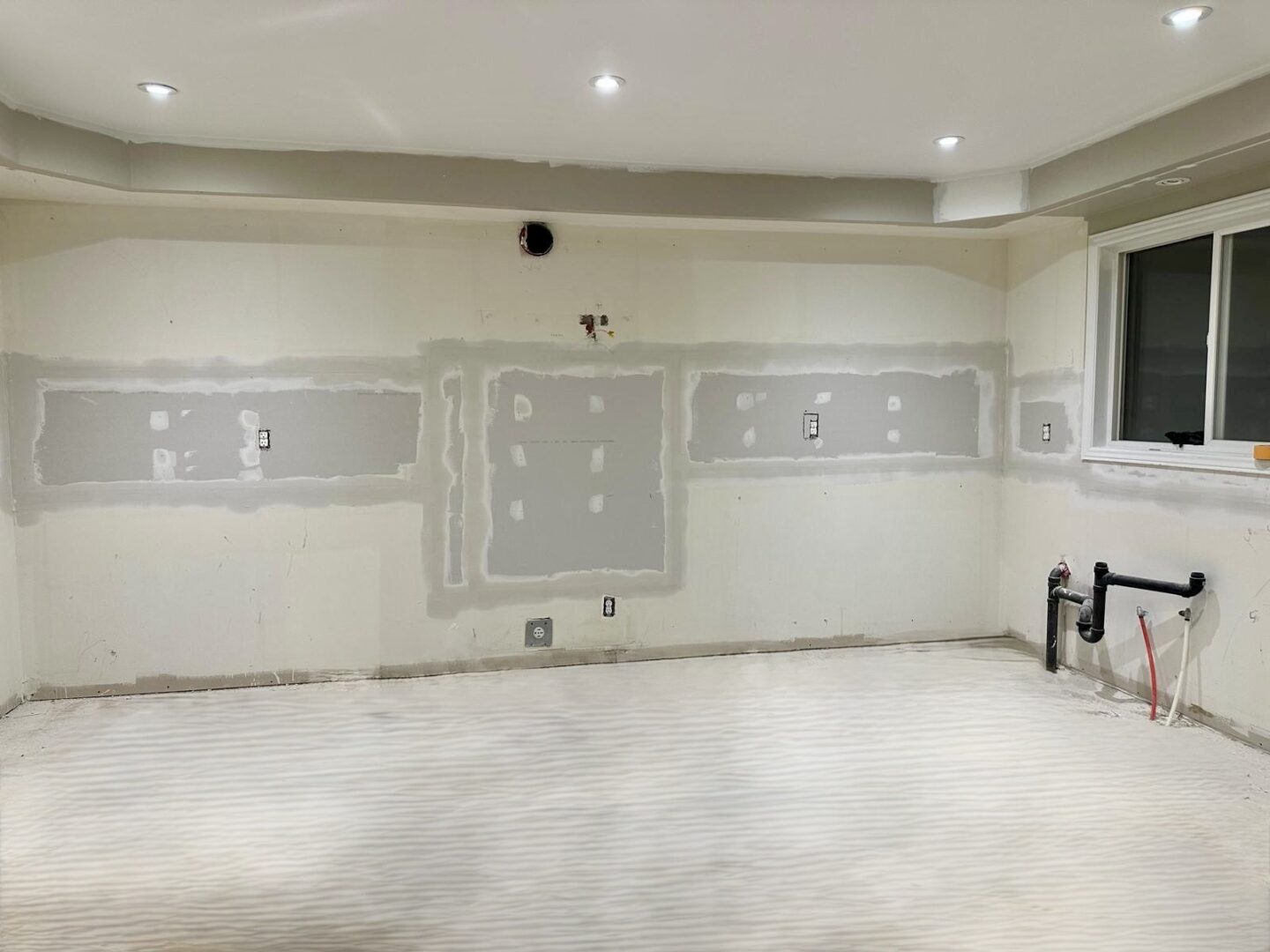 Unfinished drywall with taped seams and electrical outlets.
