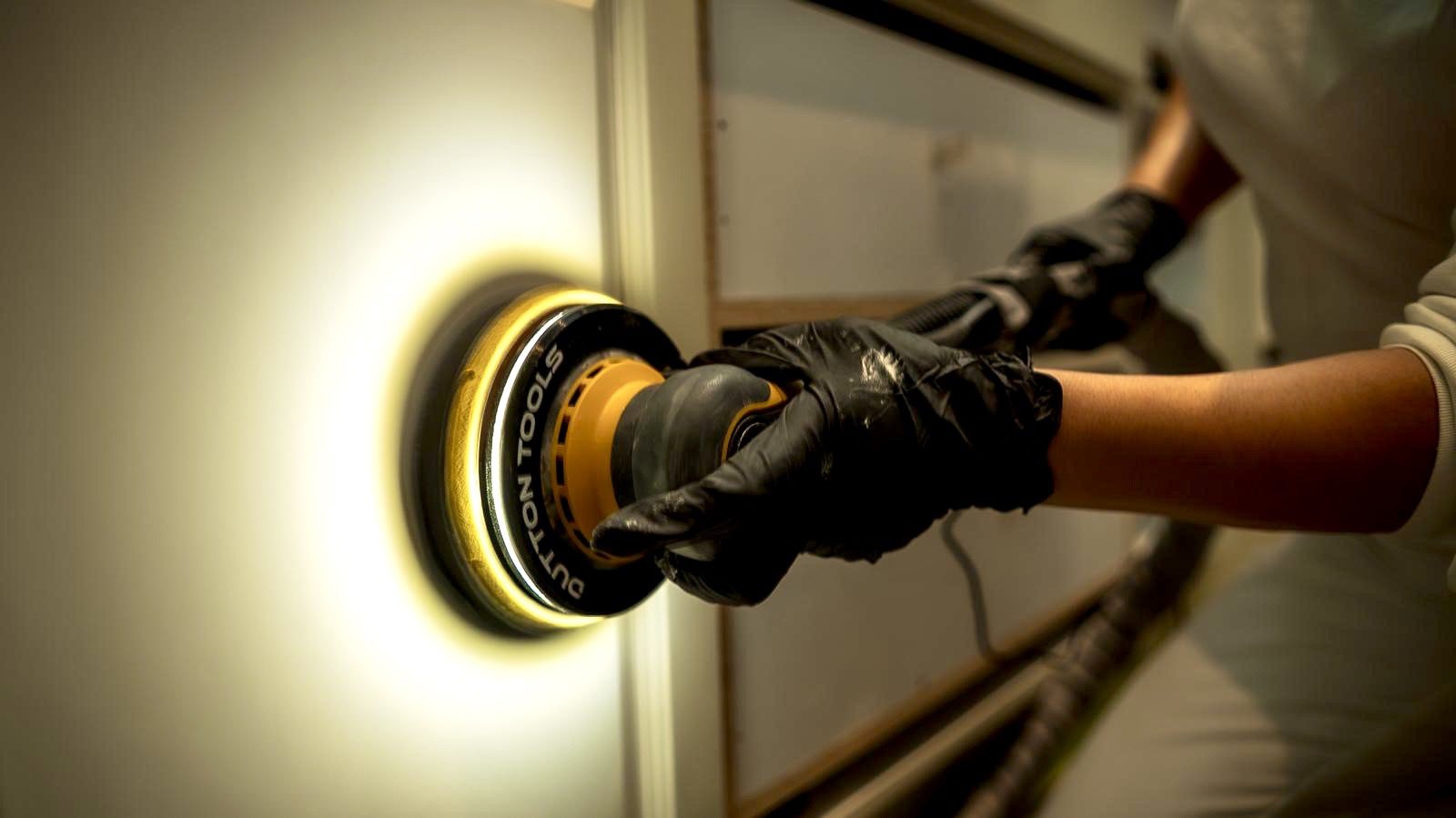 Person polishing surface with power tool.